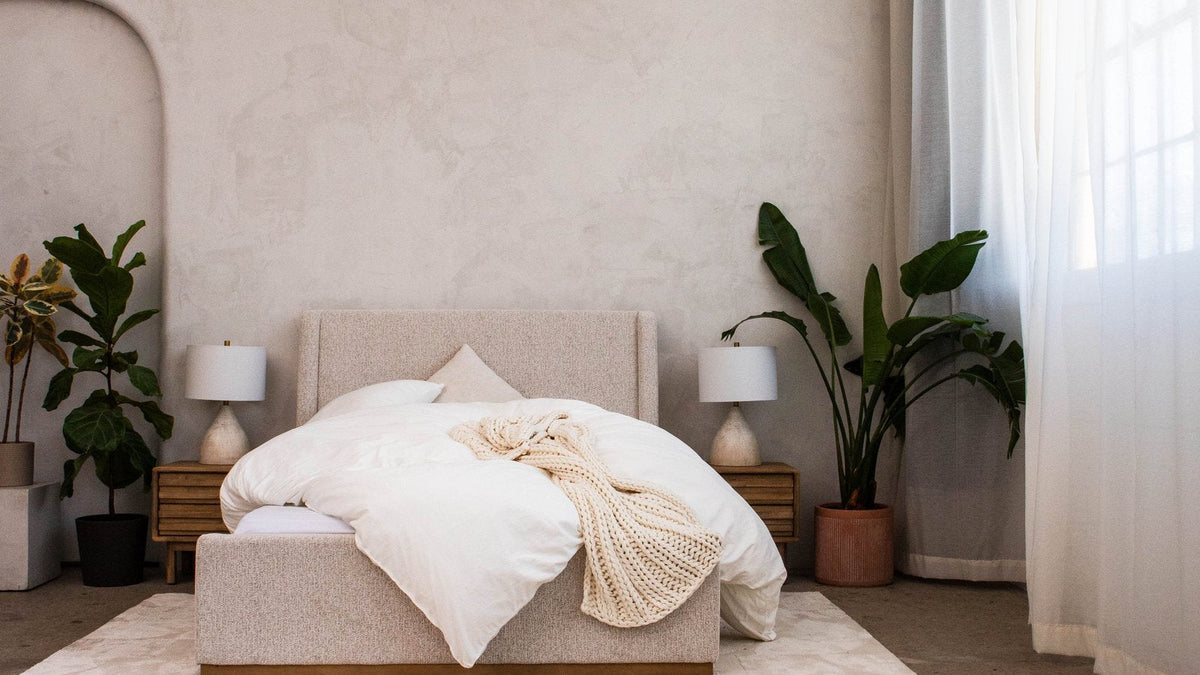 Bedroom with a white cloud duvet on the bed and plants by the window