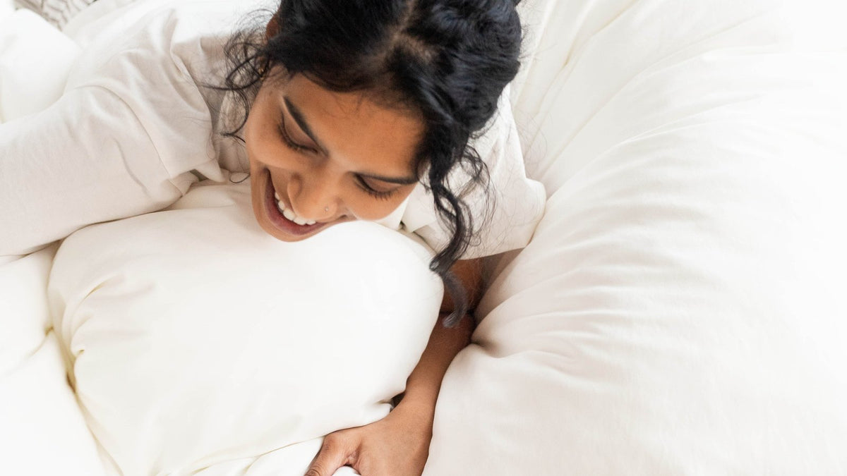 Overhead view of a woman lying on a fluffy white cloud duvet