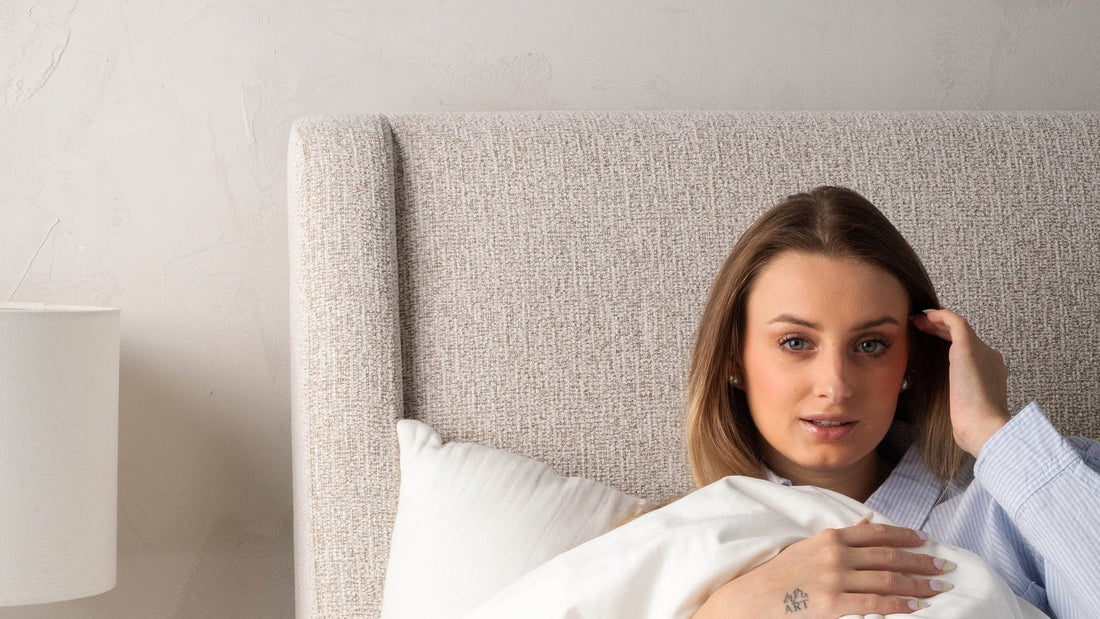 Woman sitting up in bed reading under a fluffy white cloud duvet