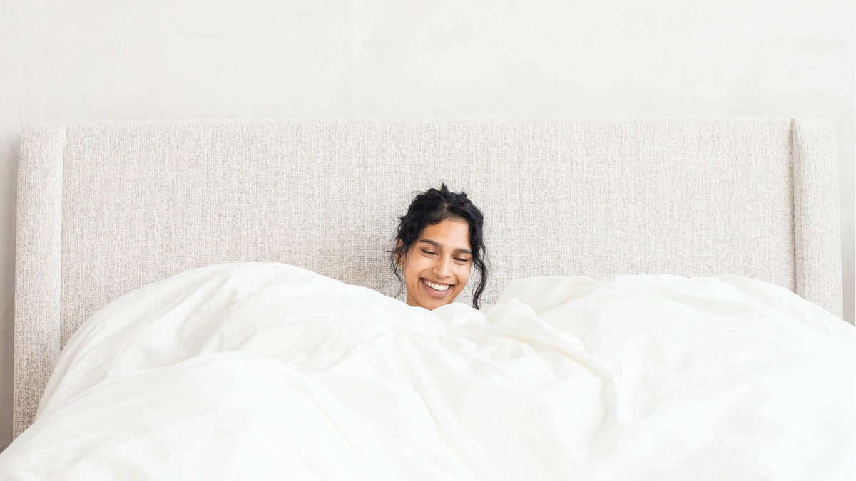 Woman sitting up in bed with the PureFlow duvet pulled up to her chest