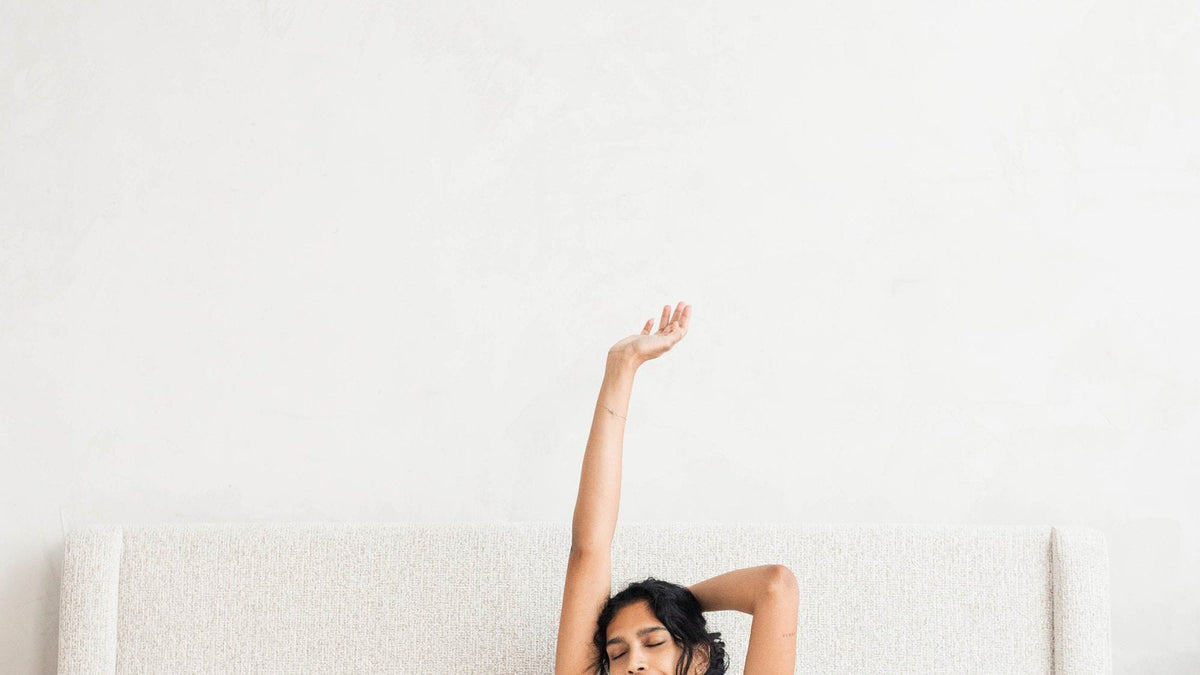 Woman stretching in bed in the morning under a white cloud duvet