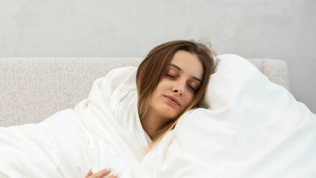 Woman wrapped in a fluffy white down alternative duvet sitting on a bed