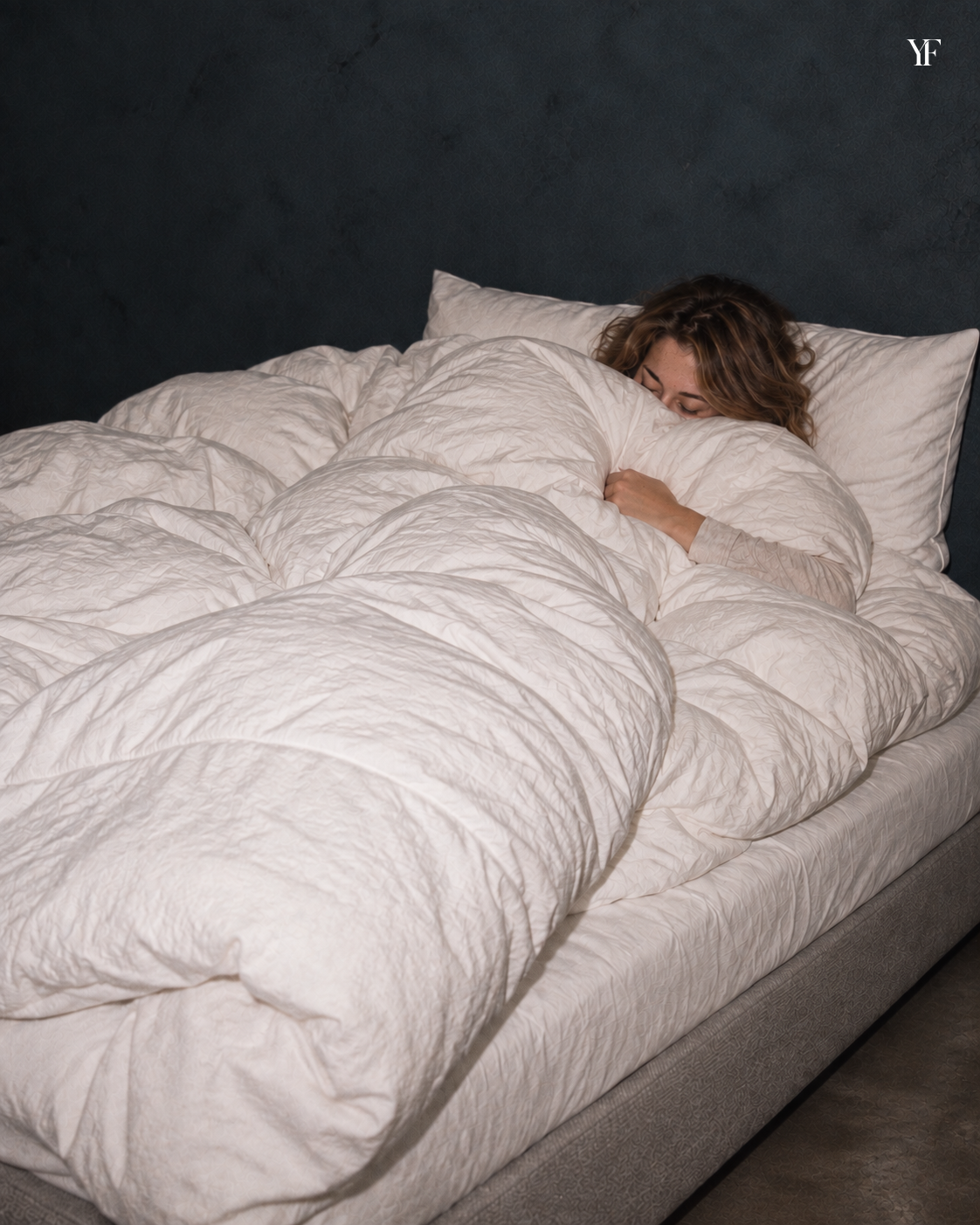 A sleeper nestled beneath the white Cloud duvet, with pillows behind them.