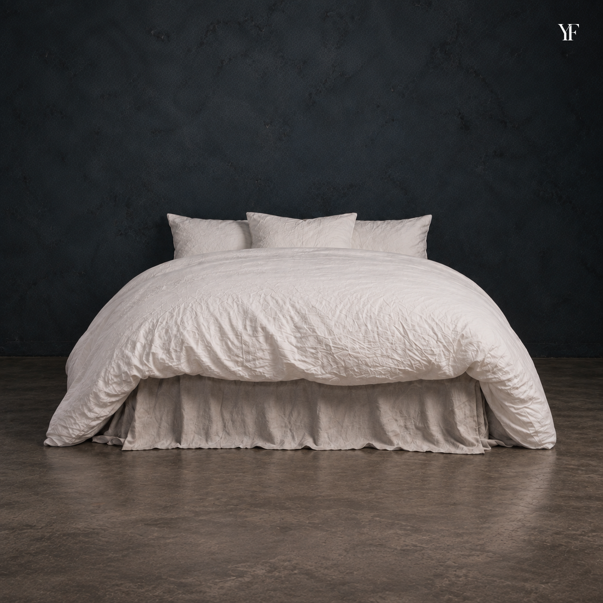 Front view of the white Cloud duvet draped over a bed against a dark studio wall.