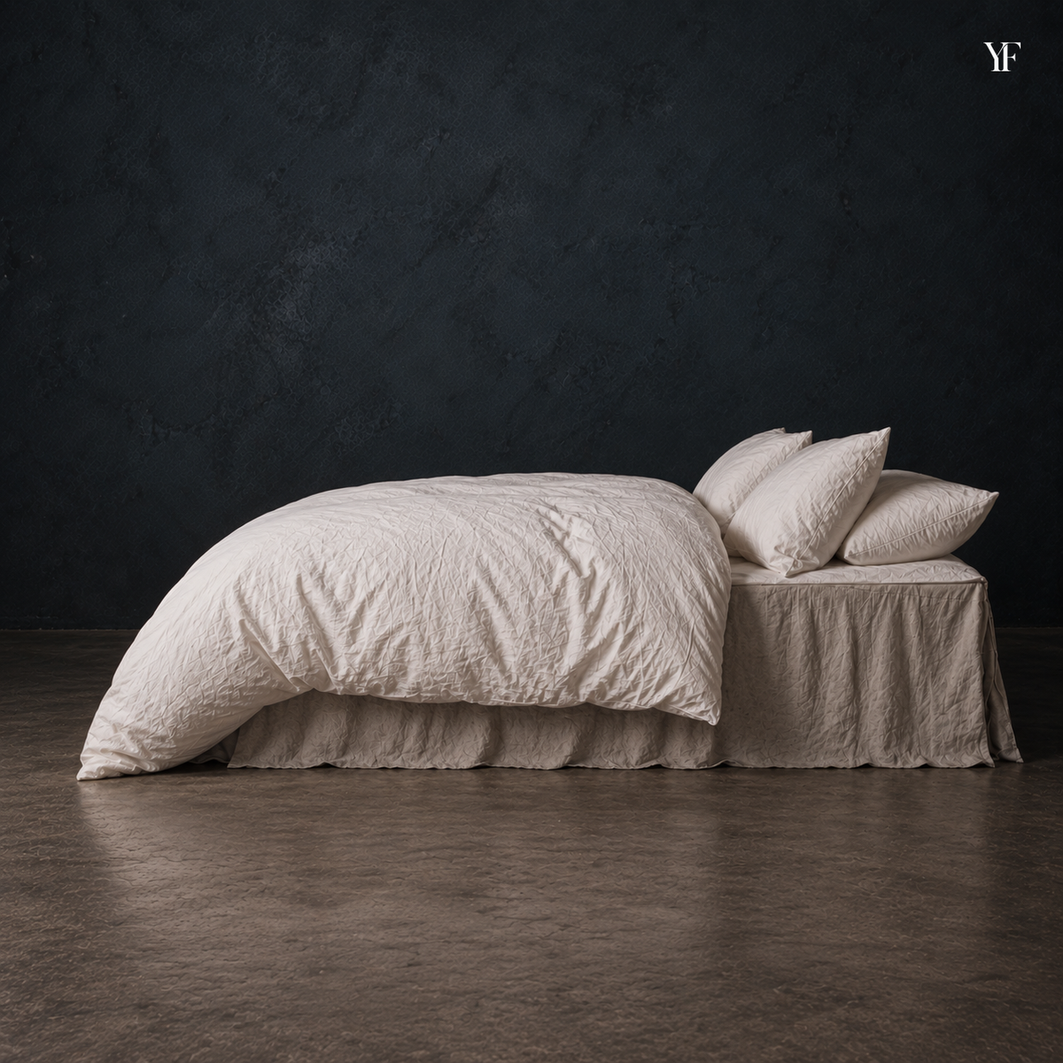 Side view of the white Cloud duvet and pillows on a bed against a dark studio wall.