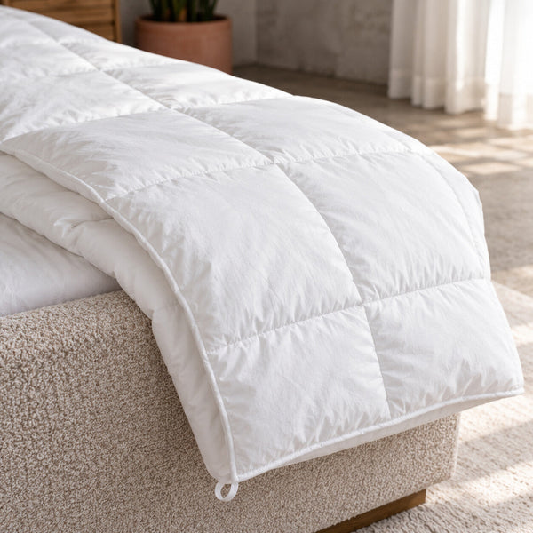 Close up of the Air duvet's sewn-through quilted boxes and corner loop over the edge of a bed