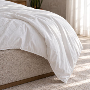 The Air duvet in its cotton percale cover draping softly over the corner of a bed