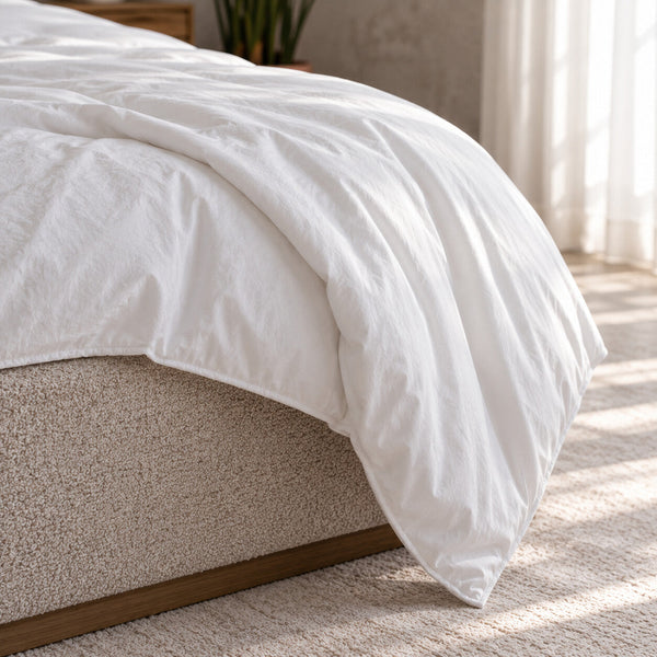 The Air duvet in its cotton percale cover draping softly over the corner of a bed