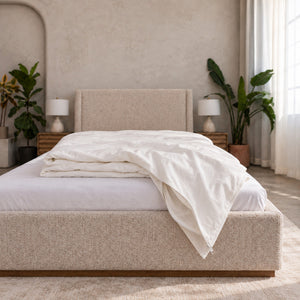 Cloud Duvet Cover in white cotton percale, loosely folded over the foot of an upholstered bed