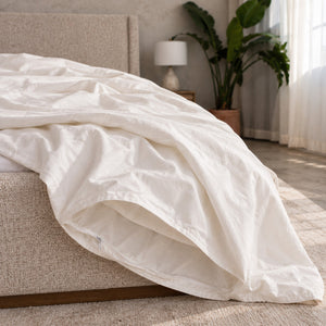 The empty Cloud Duvet Cover opened and draped over the corner of a bed, with no filling inside