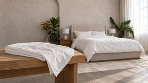 A spare Cloud Duvet Cover folded on a bench at the foot of a made bed on wash day