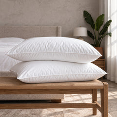 Two Cloud Pillows stacked on a wooden bench at the foot of a bed