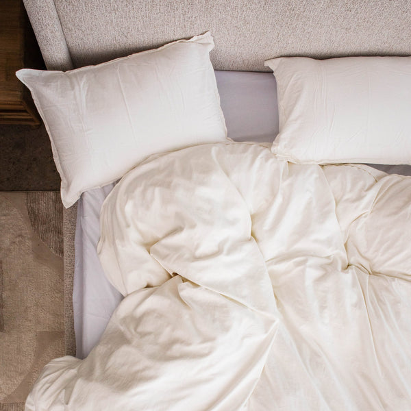 Two Cloud Pillows at the head of a bed, seen from above, with a white duvet pulled up below them