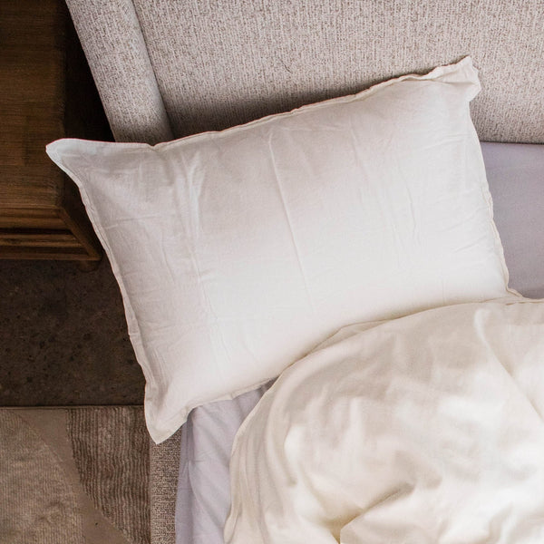 A white cotton percale Cloud Pillowcase on a pillow at the head of a bed, seen from above
