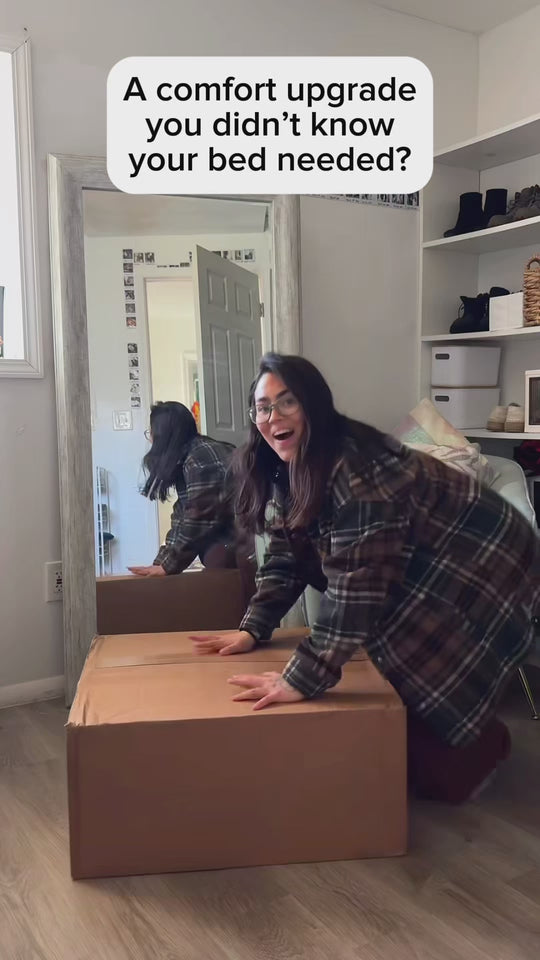 A woman opens a delivery box, pulls out a white duvet and throws it onto her bed
