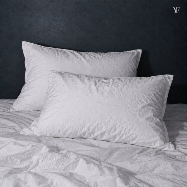 Two white Cloud Pillows on a bed with rumpled white cotton bedding