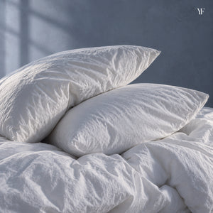 Two Royal goose down pillows resting on a gathered white duvet in soft window light