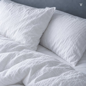 Two plump Royal goose down pillows in crisp white pillowcases, close up at the head of the bed