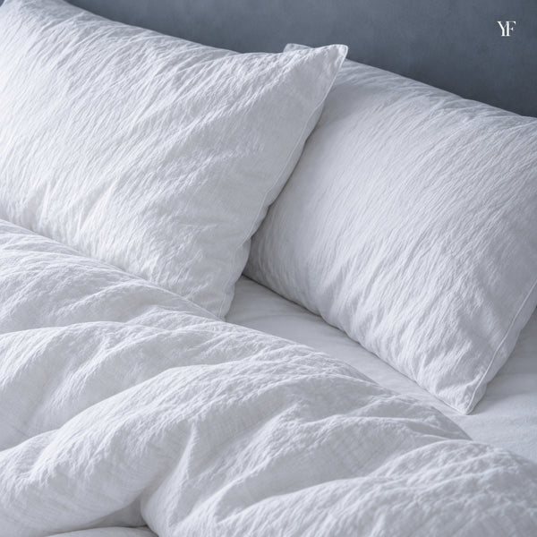 Two plump Royal goose down pillows in crisp white pillowcases, close up at the head of the bed
