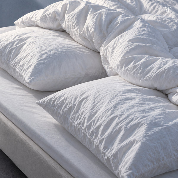 Royal goose down pillows and a gathered Royal Goose Down Duvet on a bed dressed in white cotton