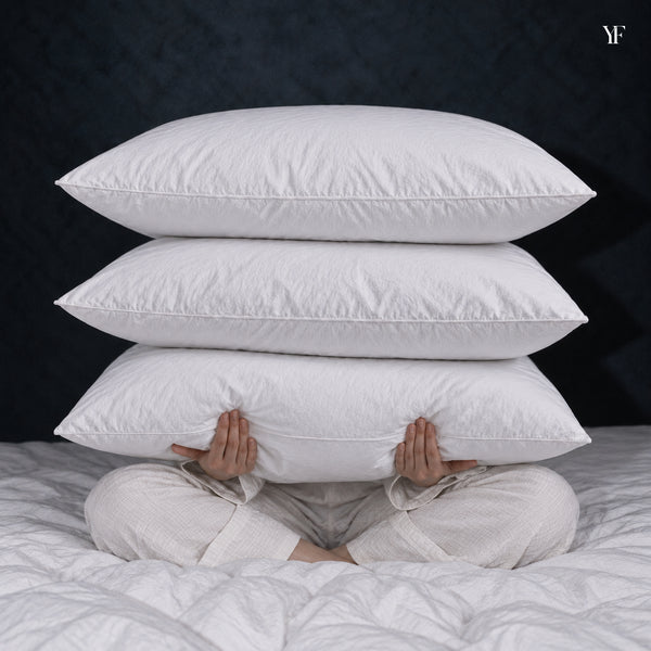 Three white Cloud Pillows stacked in a seated person's arms.
