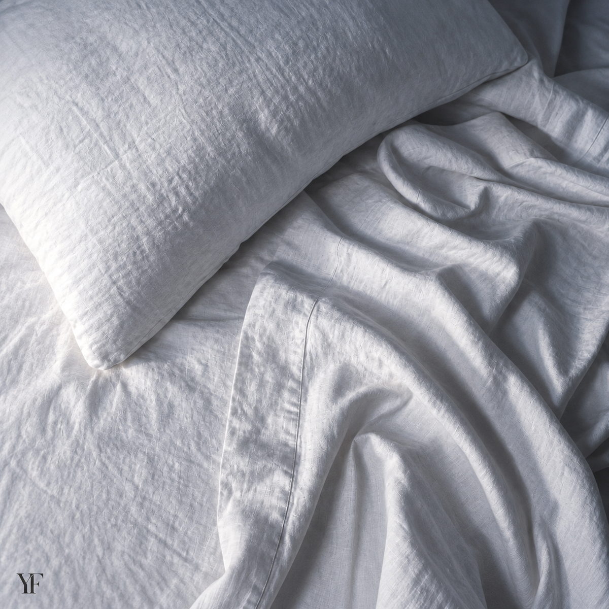 White pillowcases and sheets layered together, showing their softly wrinkled surfaces.