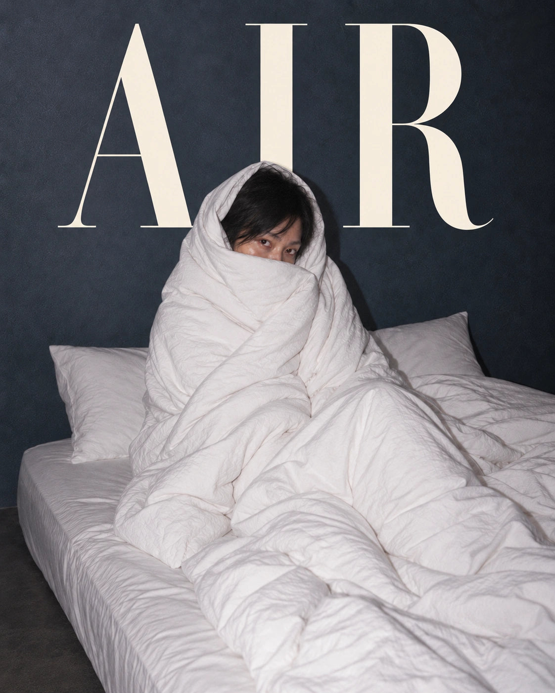 Air editorial cover: ivory AIR lettering behind the duvet-wrapped model.